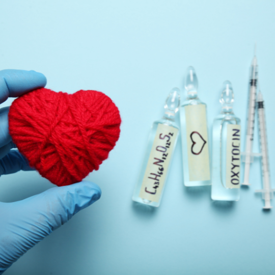 syringes and vials labeled the love hormone and oxytocin next to a heart